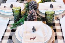 27 green glass candle holders, pinecones, wood slice chargers and greenery
