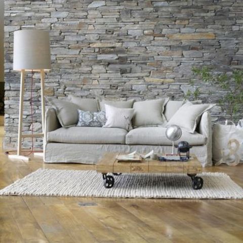 grey stone wall behind the sofa accentuates this area