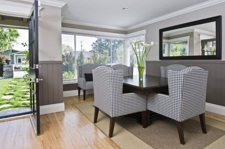 Dark grey wainscoting creates dimension and contrast in this dining area.