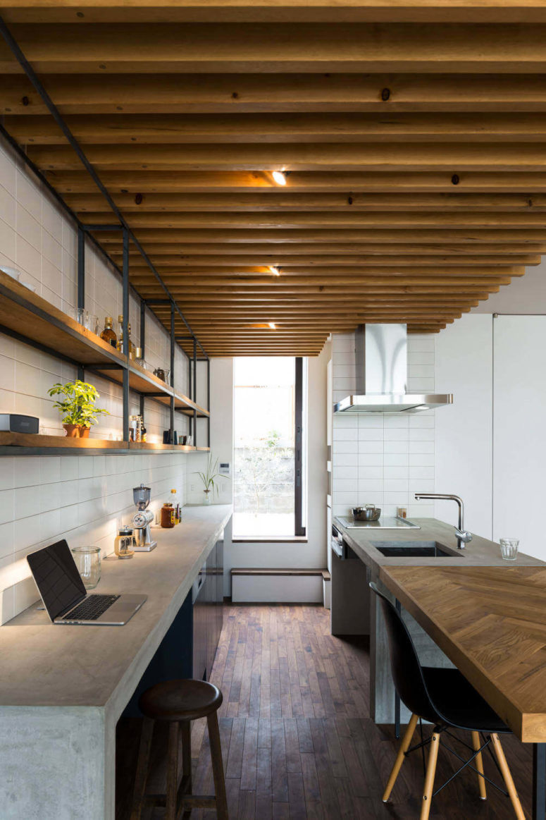 The kitchen is decorated with concrete and warm natural woods