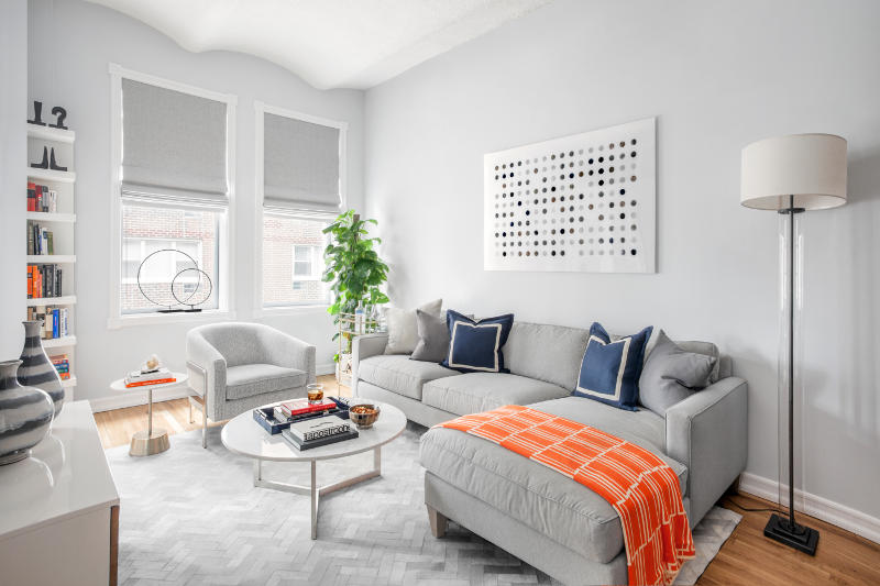 The living room is welcoming, with modern and refreshing decor and just a couple of bold touches   an orange throw and navy pillows
