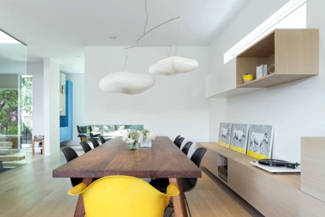 The dining space is unique with its cloud lamps, rich-colored wooden table and sunny yellow accents