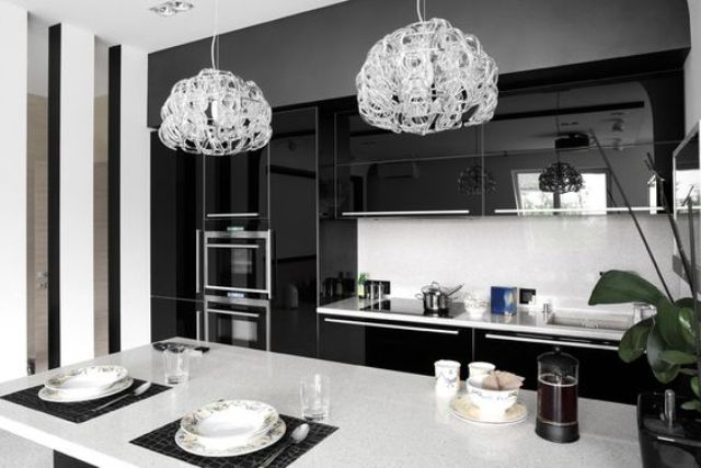 modern black and white kitchen with dual crystal pendant lights, white counter tops, and black high gloss laminate cabinets