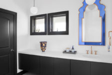 05 Black and white bathroom is spruced up with a whimsy blue frame mirror and an orange patterned rug