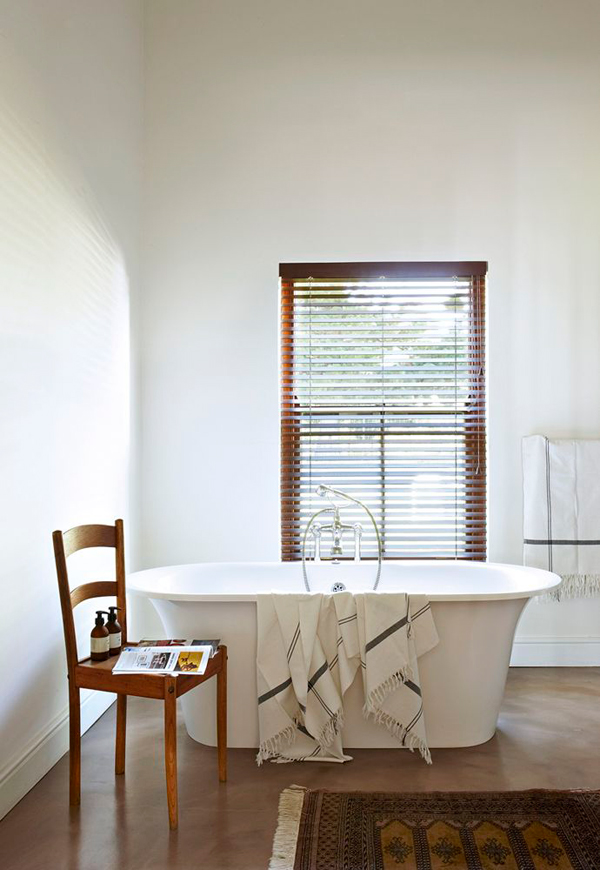 The master bathroom is an effortlessly chic place with a free standing bathtub next to the window covered with shutters