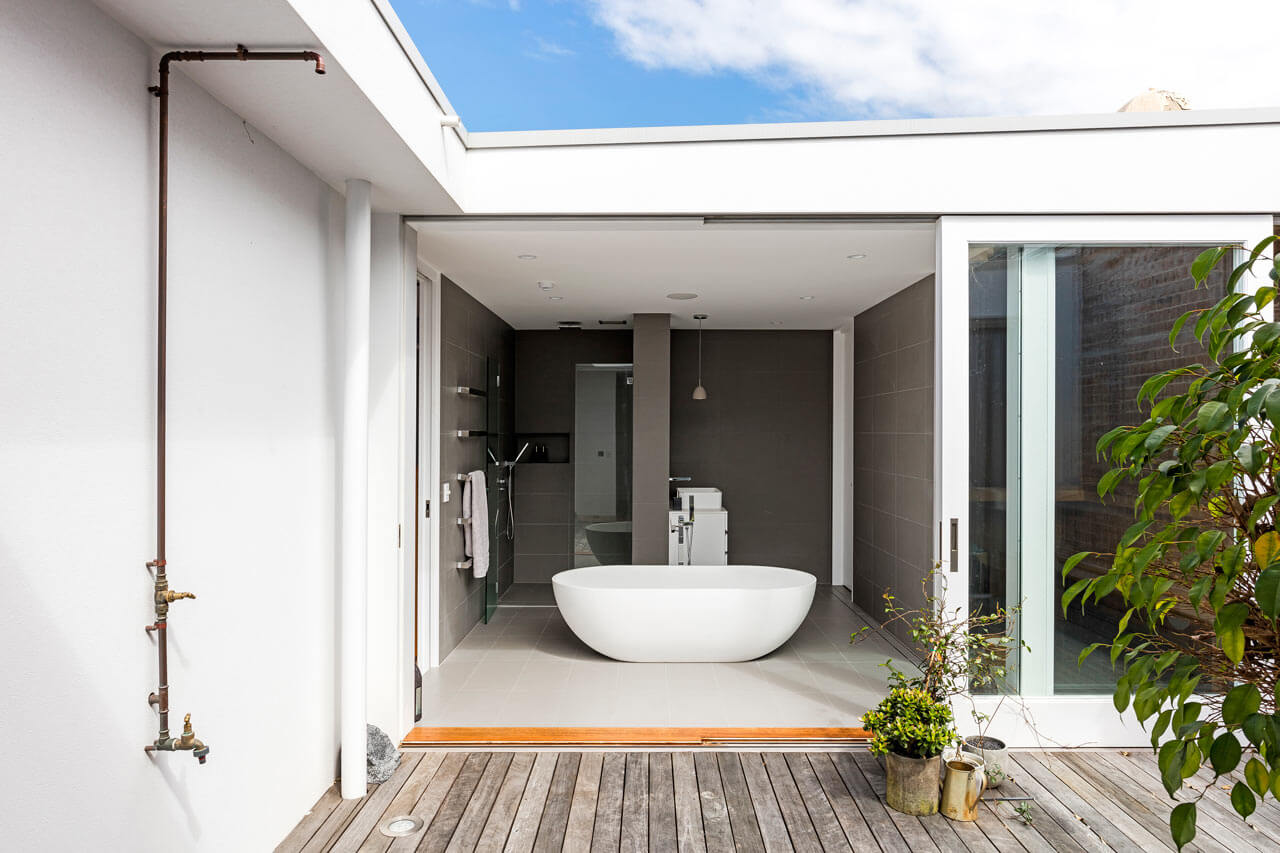 The bathroom is done in grey, with a minimalist feel, and it may be opened outside with a glass door