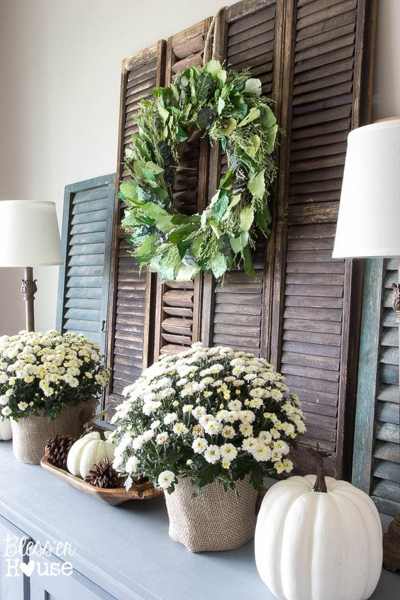 neutral fall mantel with faux pumpkins and potted flowers