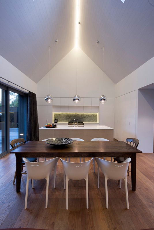 The kitchen is modern and minimalist, with a large glass door