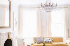 07 The living room is vintage in warm shades like ocher and buttermilk. A refined chandelier, vintage fireplace and mirror create an ambience