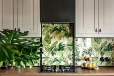 08 The kitchen mixes traditional cabinets, botanical wallpaper and natural wooden furniture