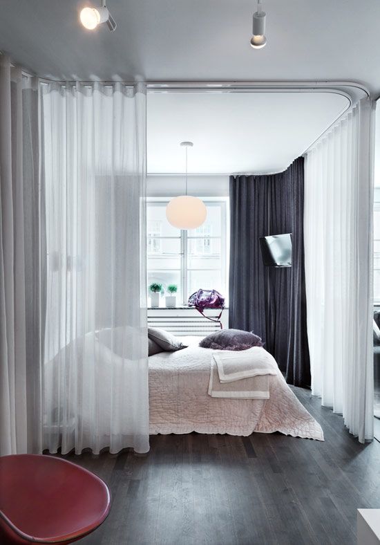 sheer white curtains divide the bedroom area from all the rest of the apartment