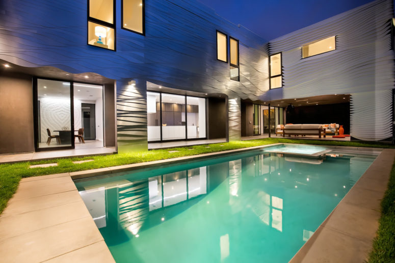 Almost every space is opened to the large pool, and the outer clad of the house reminds of the ocean waves