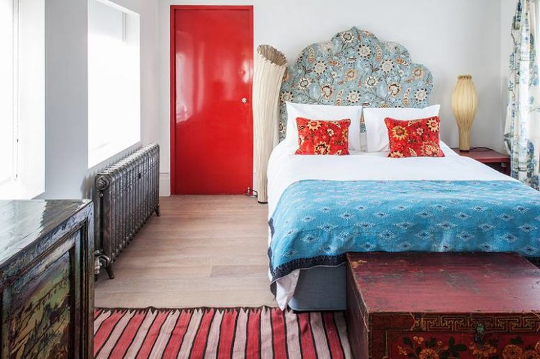 The master bedroom looks like a bold artwork, there's a bold red door, a vintage radiator, oriental textiles and a headboard