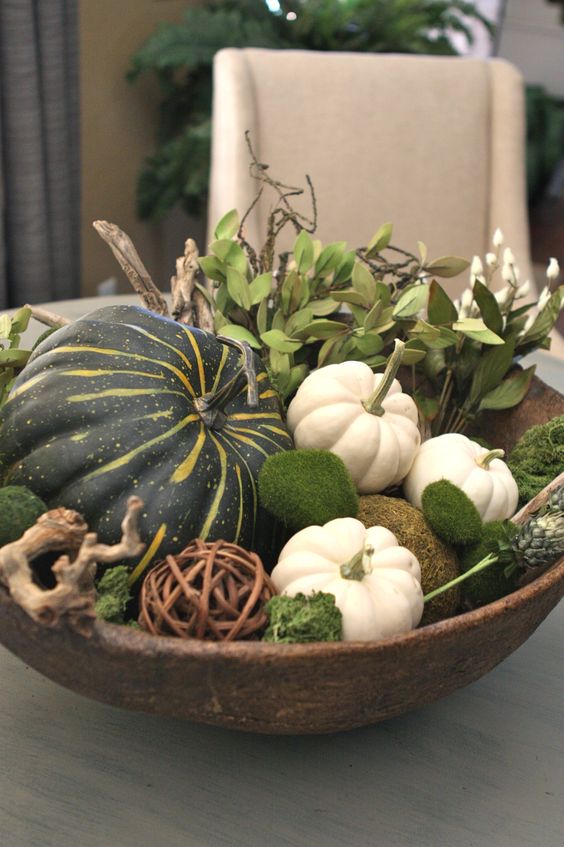 wooden bowl filled with leaves, gourds, pumpkins and moss