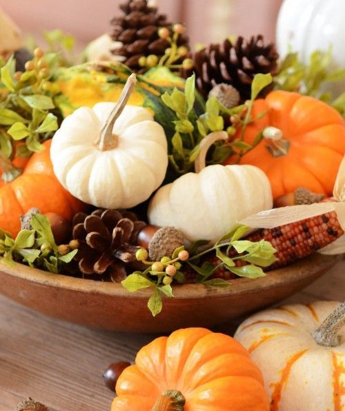wooden bowl filled with pumpkins, corn, pinecones and greenery