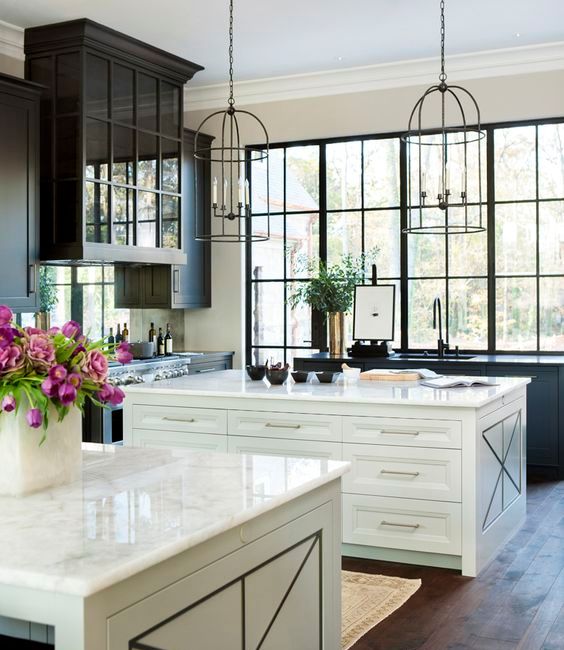 airy kitchen with two white kitchen islands and a large black framed window