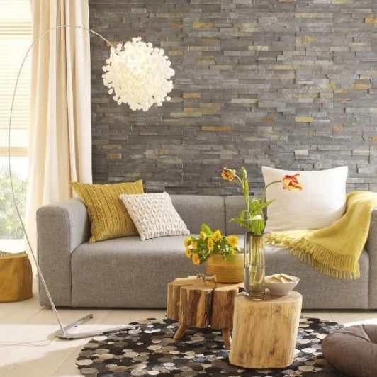 grey stone accent wall, a dove grey sofa and yellow textiles