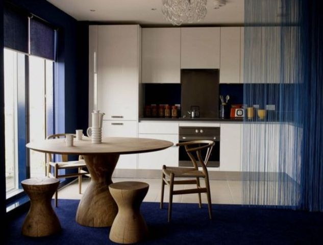 sheer blue curtain continues the decor and divides the dining zone from the kitchen