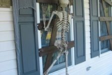 19 cardboard affixed to window to make it look boarded up and skeleton proped to look like it’s trying to get in