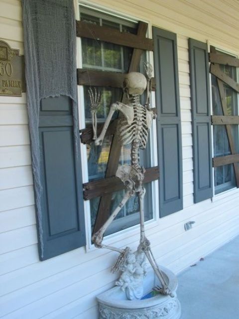 cardboard affixed to window to make it look boarded up and skeleton proped to look like it's trying to get in