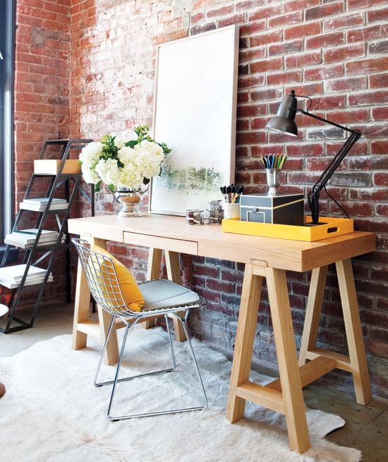 chic modern home office with a red brick wall and a wooden desk