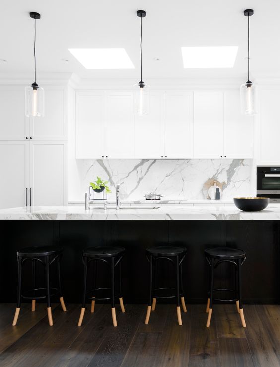 white marble benchtops and splashback, white shaker cabinets with minimal black handles, glass pendant lights with black cords
