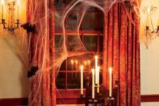 21 Halloween window decor with faux spiderweb, bats and a vintage candle holder