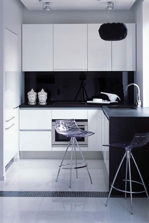 tiny kitchen with a glossy black backsplash and transparent stools