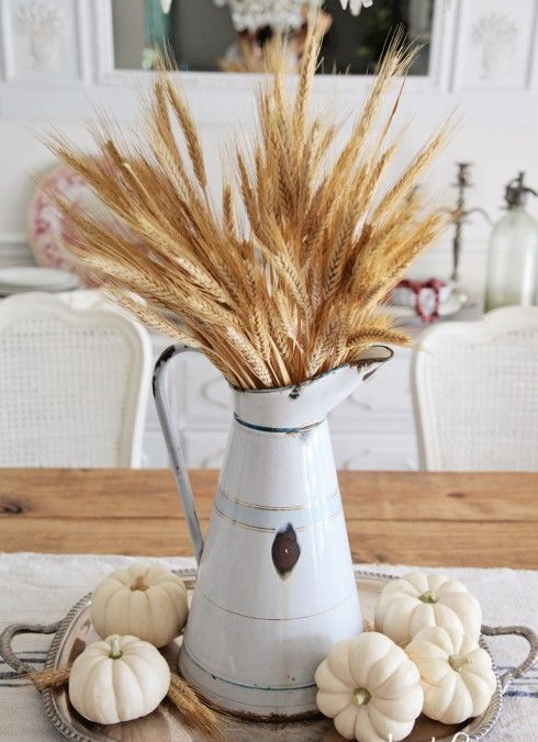 centerpiece with small pumpkins and wheat in a metal pitcher