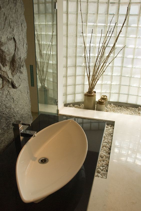 rough stone wall and pebbles on the floor give an Asian feel to this bathroom