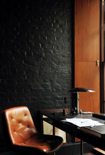 Mid century modern office with warm woods and leather is accentuated with a black brick wall
