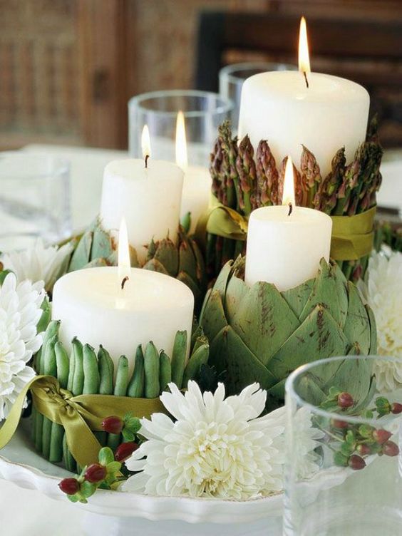 dish centerpiece with candles covered with artichokes, asparagus and peas