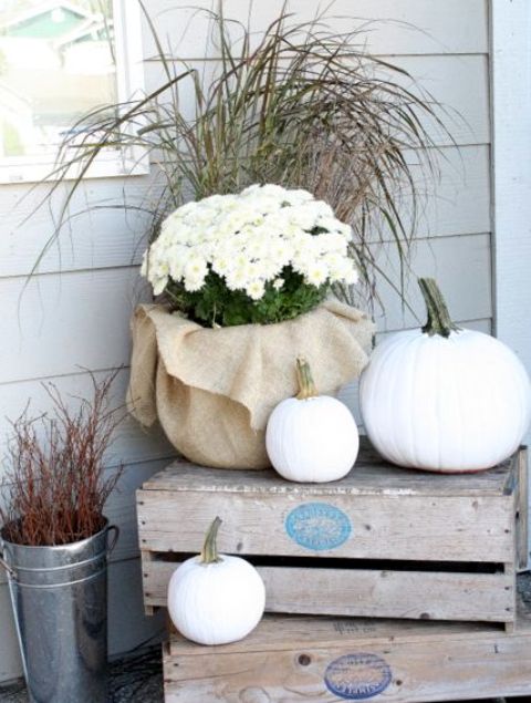 outdoor crate display with white pumpkins and potted flowers