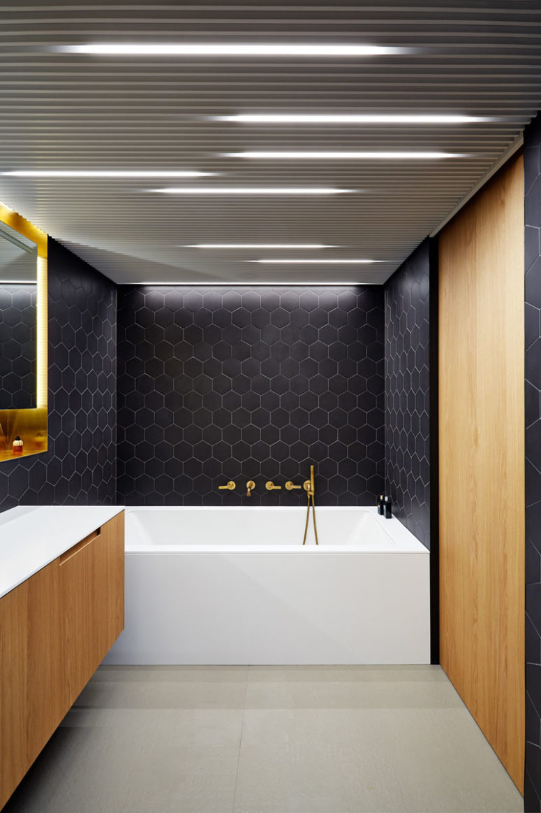 Hexagon black tiles make it special, eye-catching and stylish, and wood cabinets soften the black look