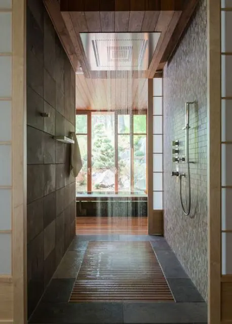 Japanese-styled bathroom in dark earthy colors, with a rain shower and wood floor