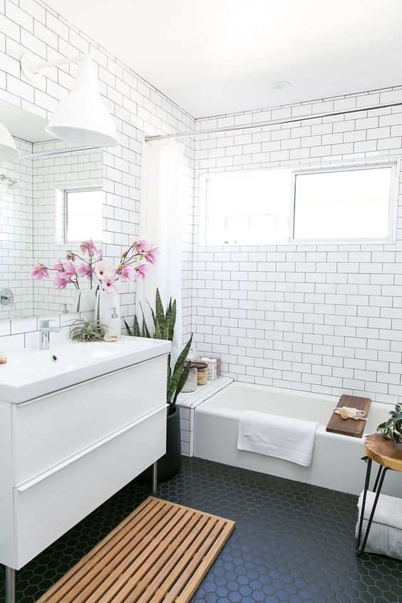 a mid-century modern bathroom with white subway tiles on the walls and black hexagon ones on the floor that work nice with each other