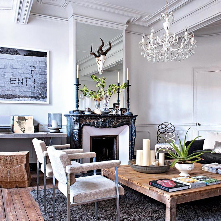 The living room blends classical antique French decor features, rough wood pieces and modern artworks