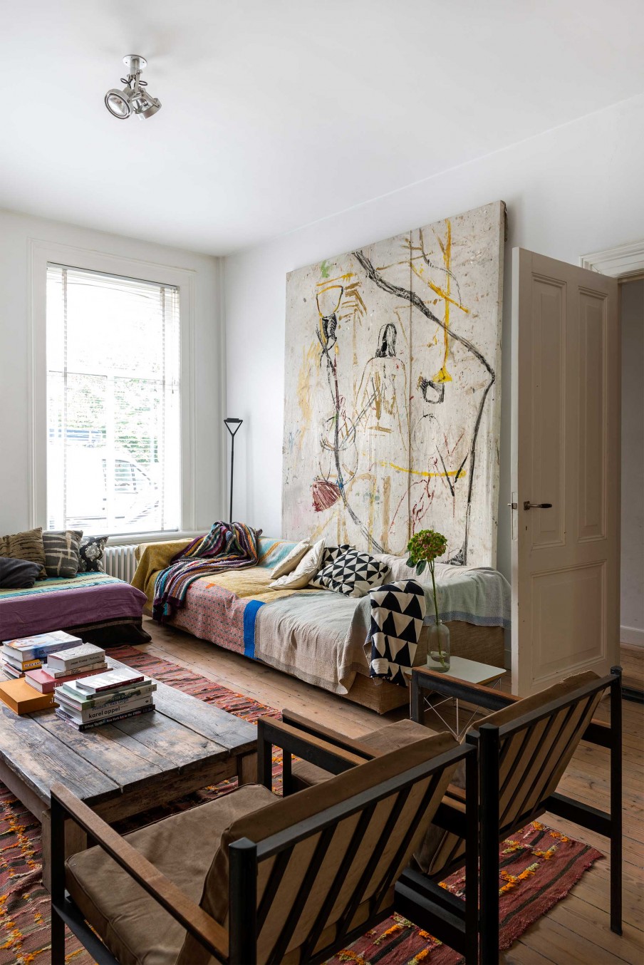 The living room has leather chairs, artworks of the owner and bold boho textiles, it's eclectic