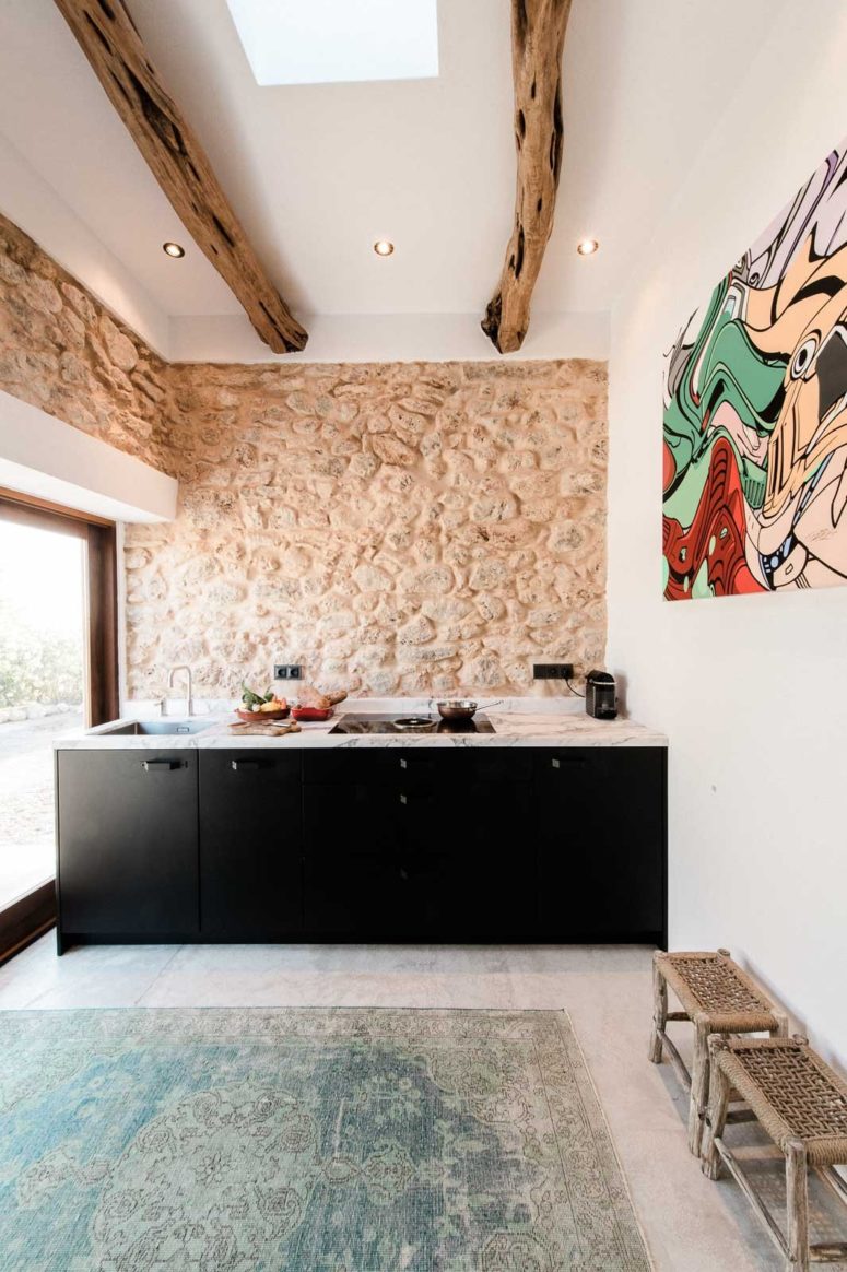The kitchen features original stone clad used as a backsplash and original exposed wooden beams yet minimalist furniture