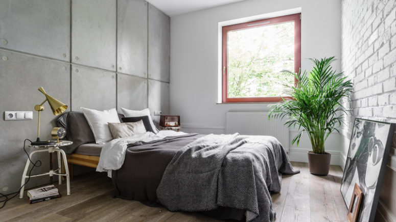 The bedroom is covered with concrete and brick panels, and potted greenery enliven the greyish space
