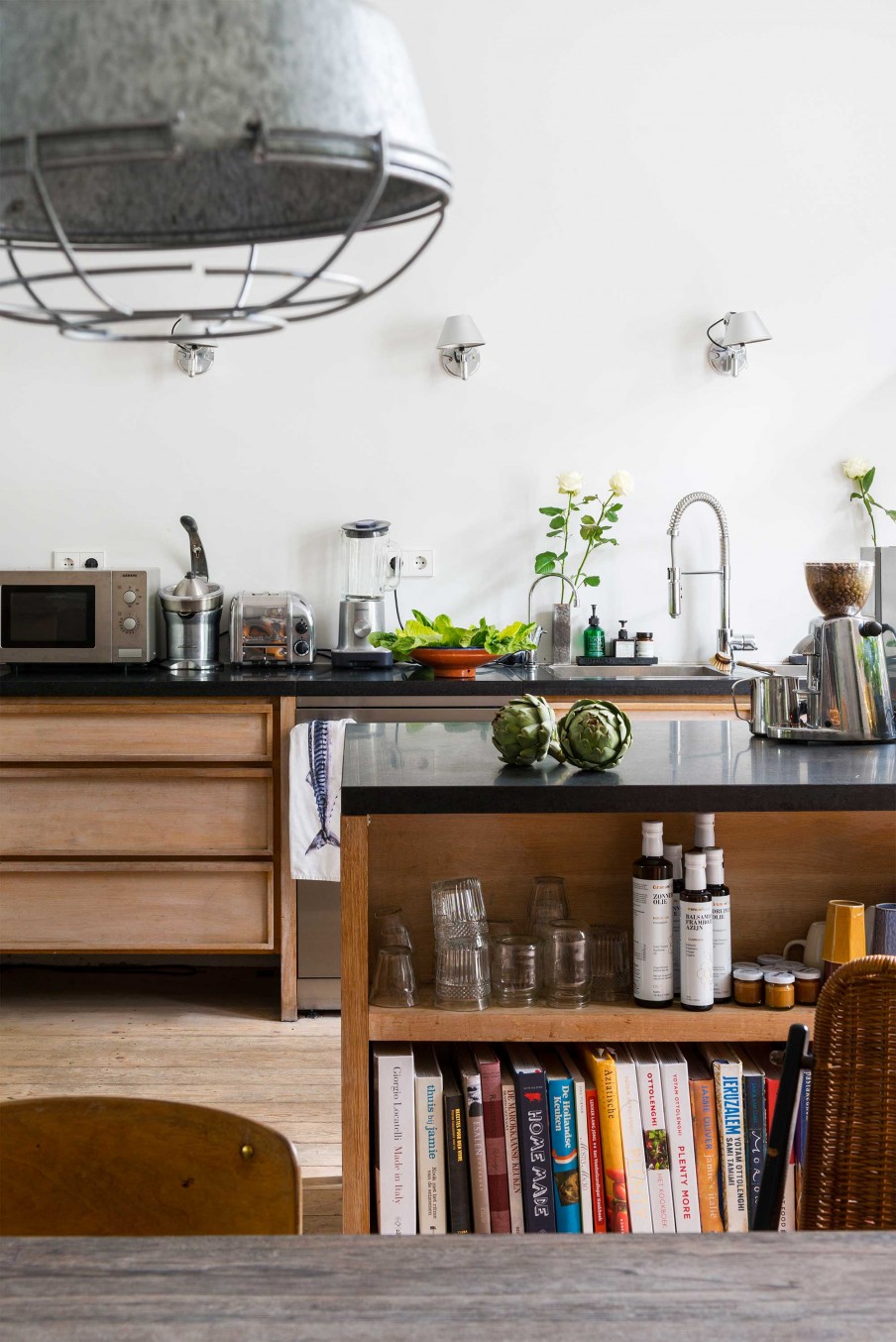 The kitchen features sleek black surfaces, wooden cabinets and floor, it's filled with light and not as whimsy as other areas. The kitchen island features some storage space.