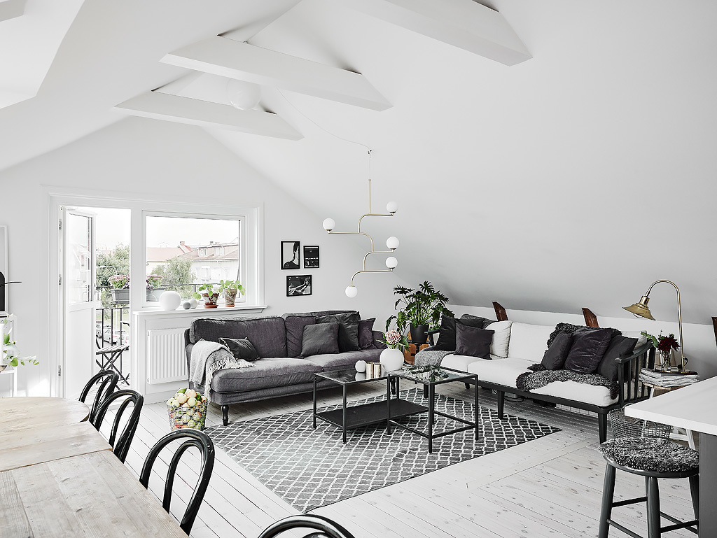 The living space features two sofas in grey and white, mid century modern lamps and textiles bring coziness