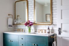 a beautiful and glam bathroom with white subway tiles, a bold green vanity, mirrors in gold frames, gold fixtures and lamps