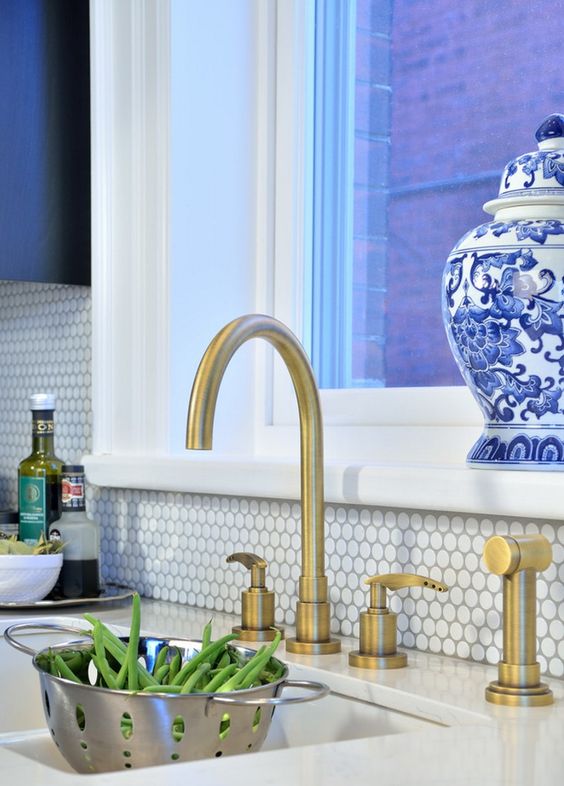 kitchen with white penny tiles and brass faucets