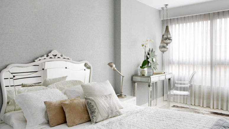 The bedroom is glam, with a mirrored bed and table and a cool lucite chair