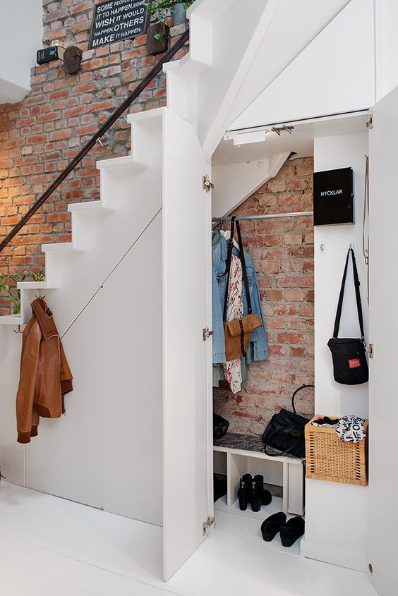 entryway cabinet and bench under the stairs features a brick wall that continues above