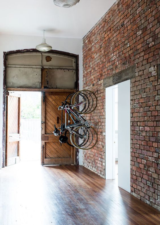 large entryway with an exposed brick wall that features bike holders