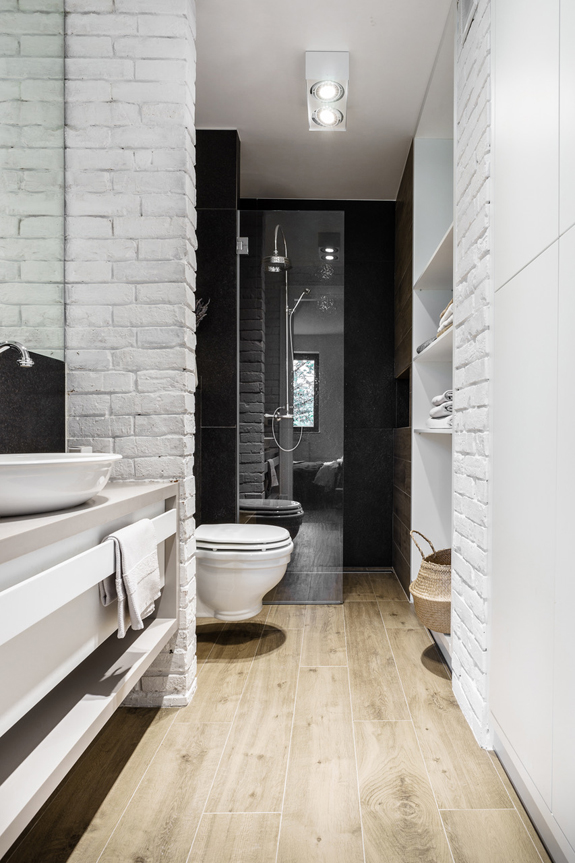 The bathroom is covered with whitewashed brick panels and features sleek surfaces