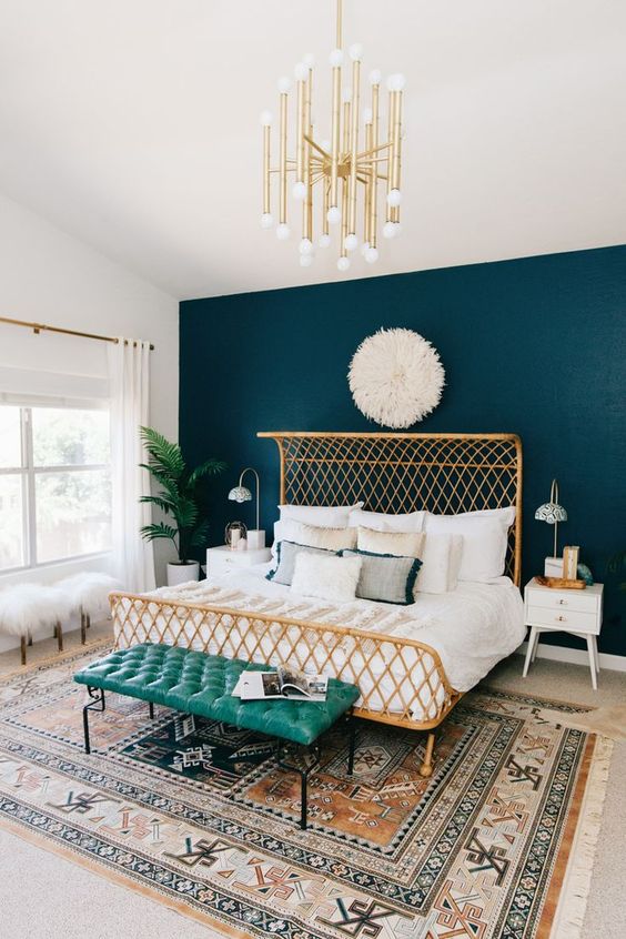 masculine meets feminine bedroom with a teal headboard wall and gilded accessories