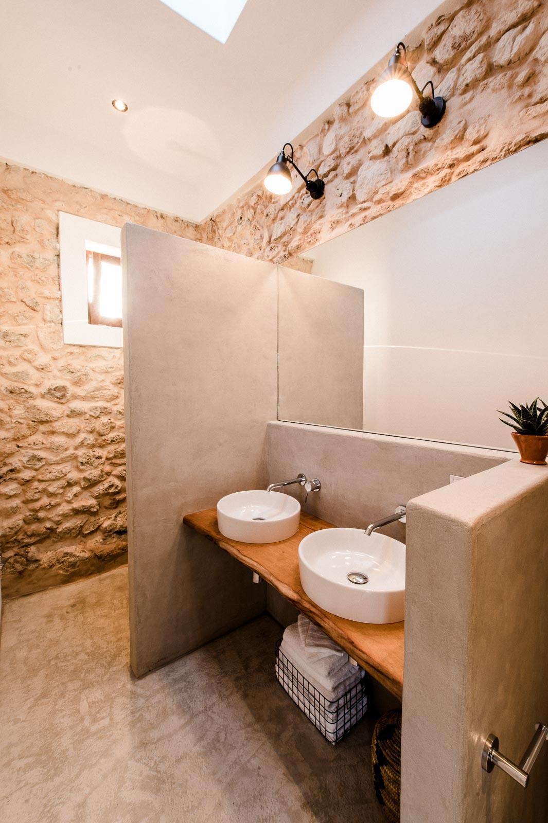 The bathroom mixes traditional stone, concrete and some warm woods that look amazing together